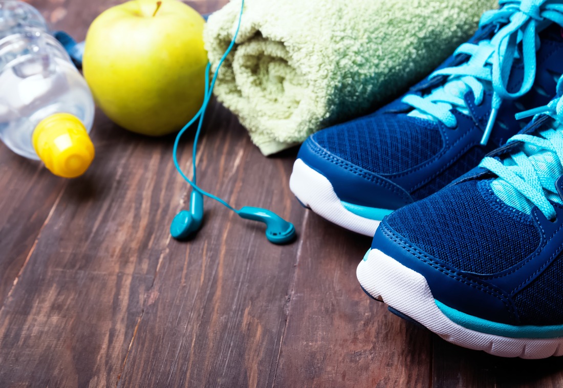 Sneakers, water, towel and earphones on the wooden background