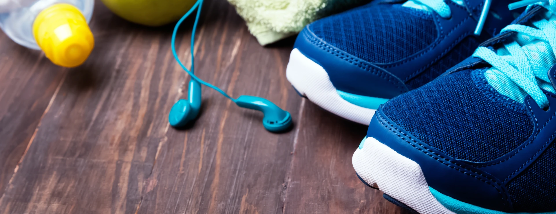 Sneakers, water, towel and earphones on the wooden background
