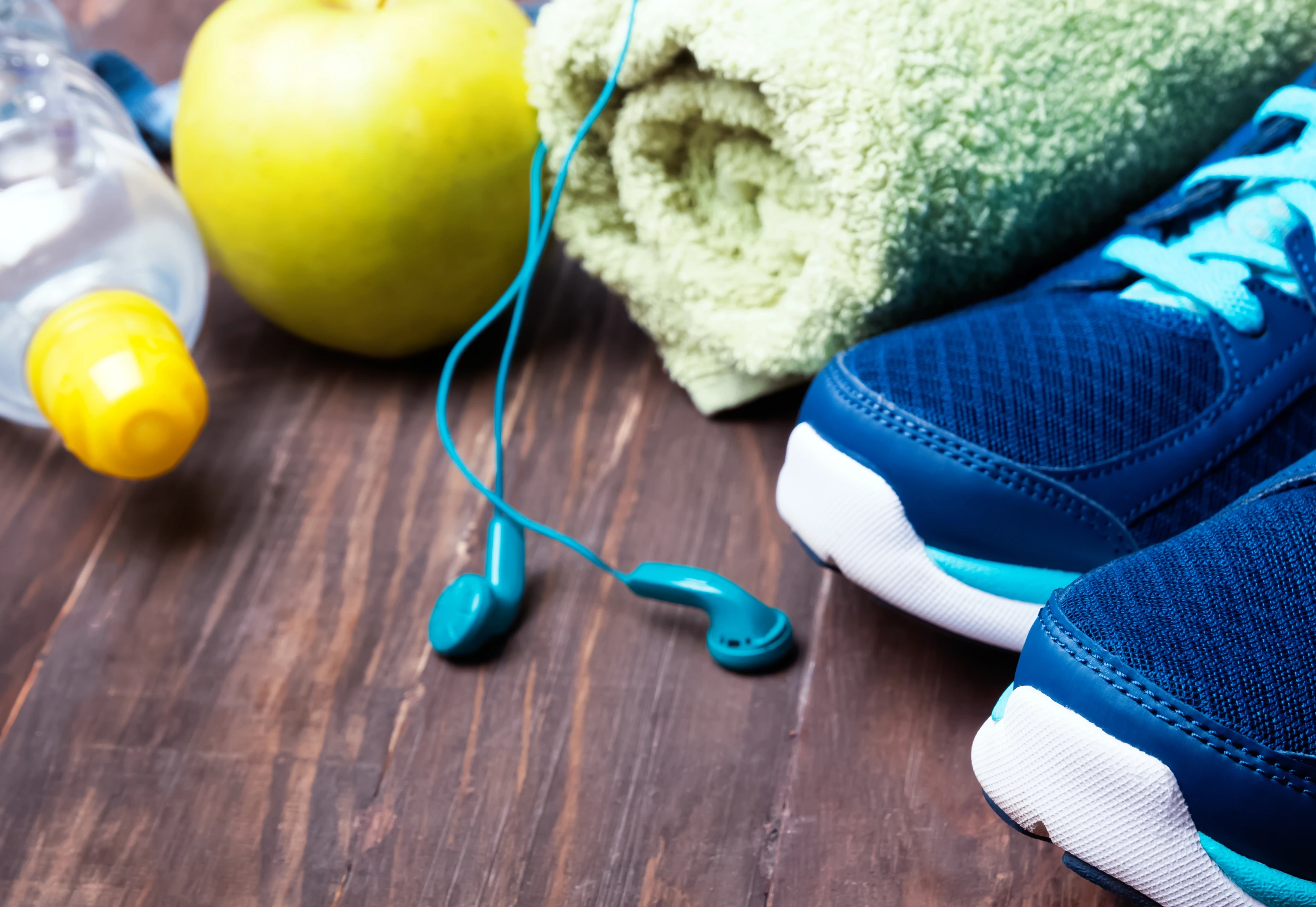 Sneakers, water, towel and earphones on the wooden background