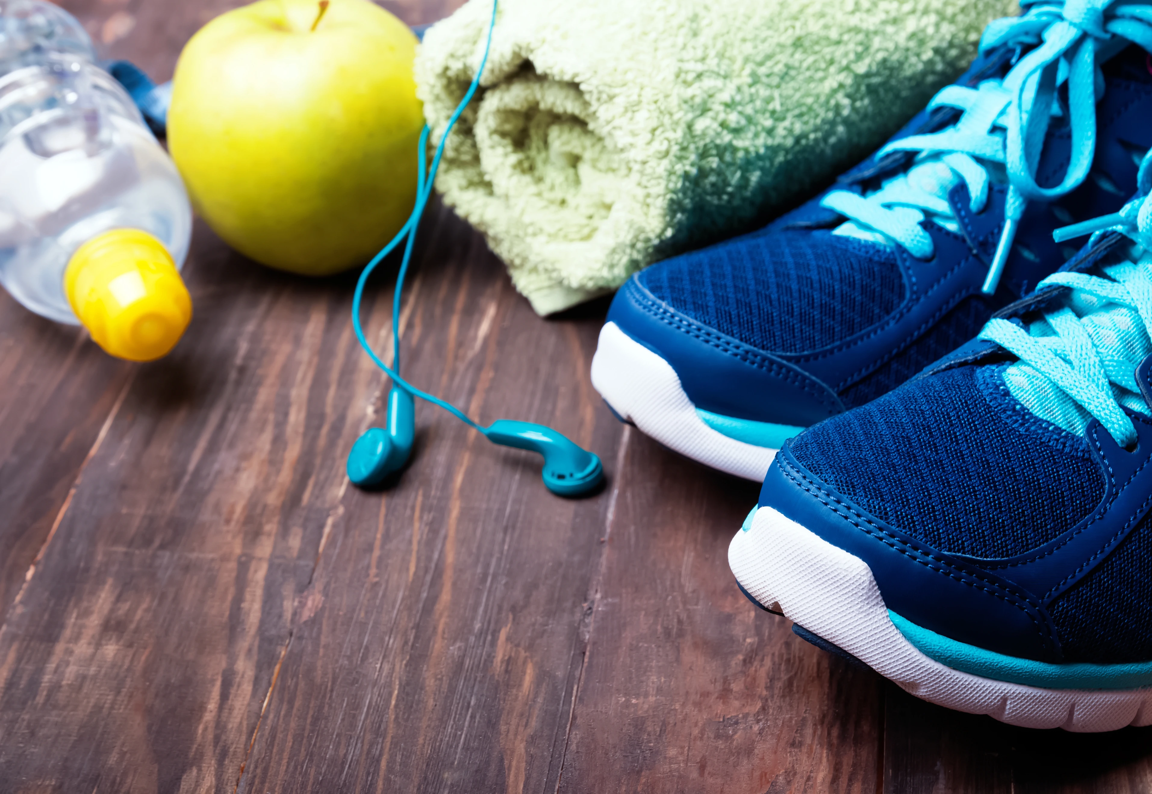 Sneakers, water, towel and earphones on the wooden background