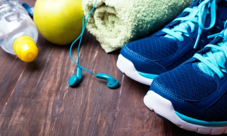Sneakers, water, towel and earphones on the wooden background