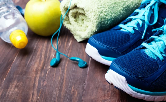Sneakers, water, towel and earphones on the wooden background
