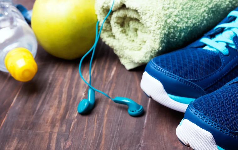Sneakers, water, towel and earphones on the wooden background