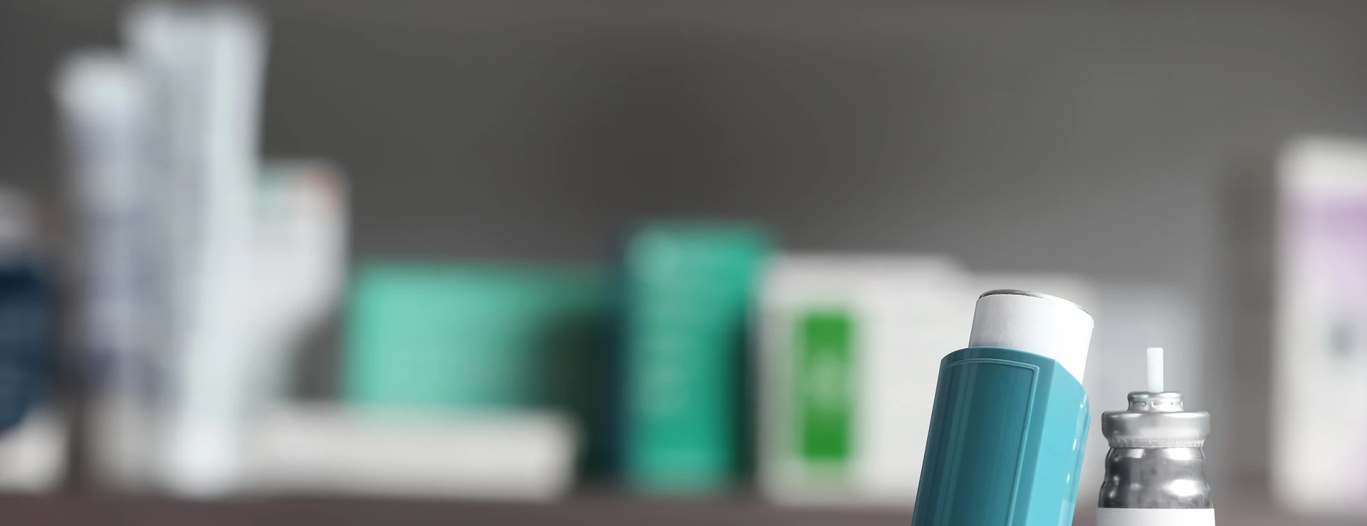 Asthma inhalers on table against blurred background. Space for text