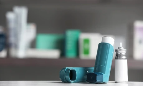 Asthma inhalers on table against blurred background. Space for text