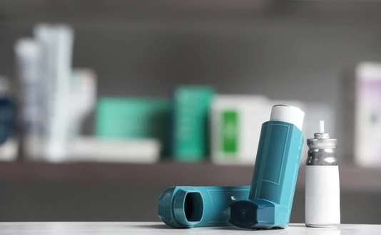 Asthma inhalers on table against blurred background. Space for text
