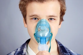 Young boy using nebulizer for asthma and respiratory diseases on light background