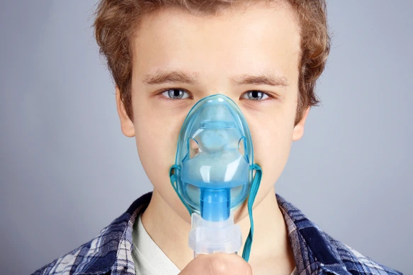 Young boy using nebulizer for asthma and respiratory diseases on light background