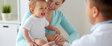 happy woman with baby and doctor at clinic