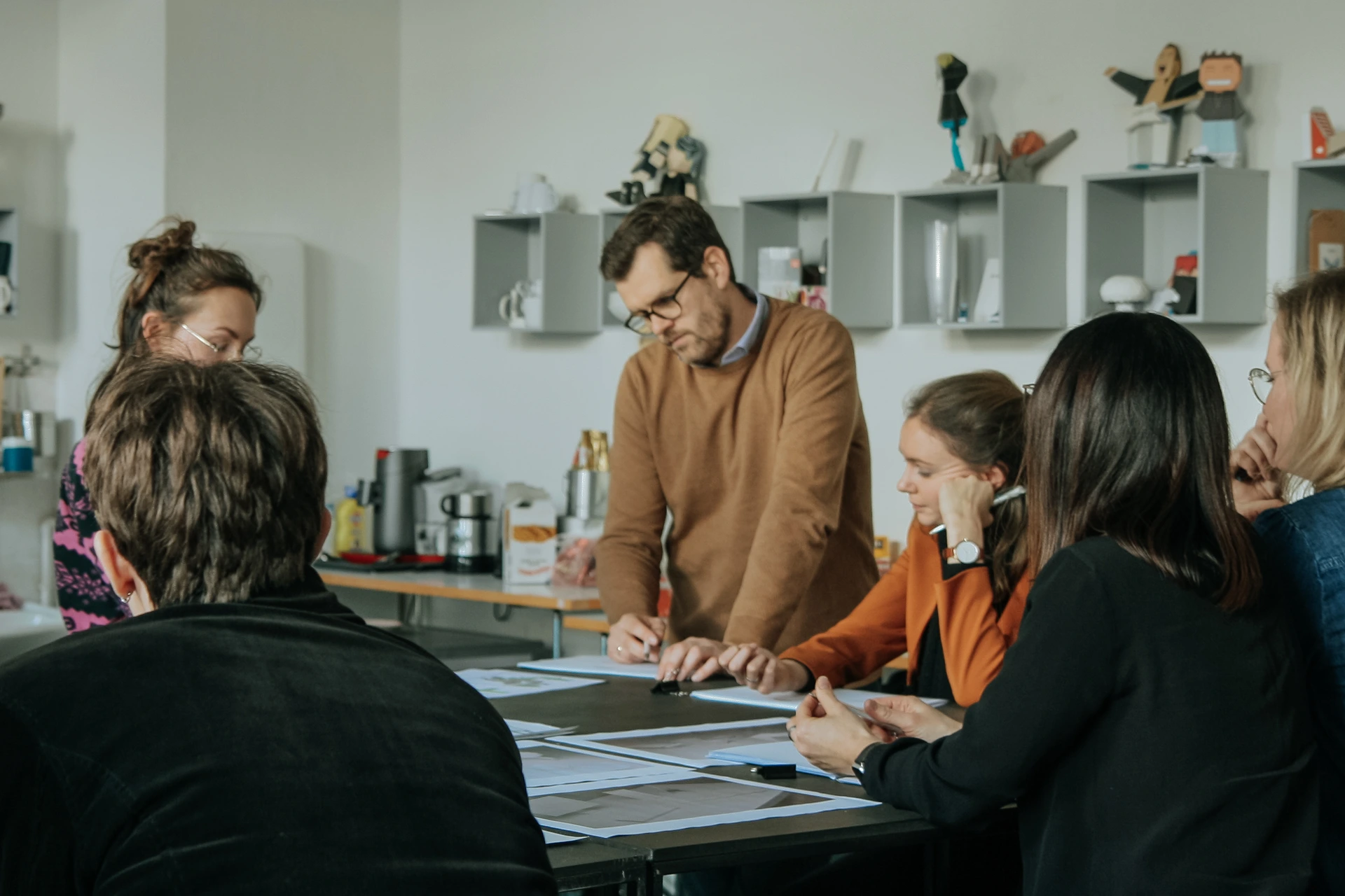 PALMBERG-Workshop im Kreativraum der Hochschule Anhalt in Dessau: Sechs Personen diskutieren gemeinsam Designskizzen an einem Tisch.