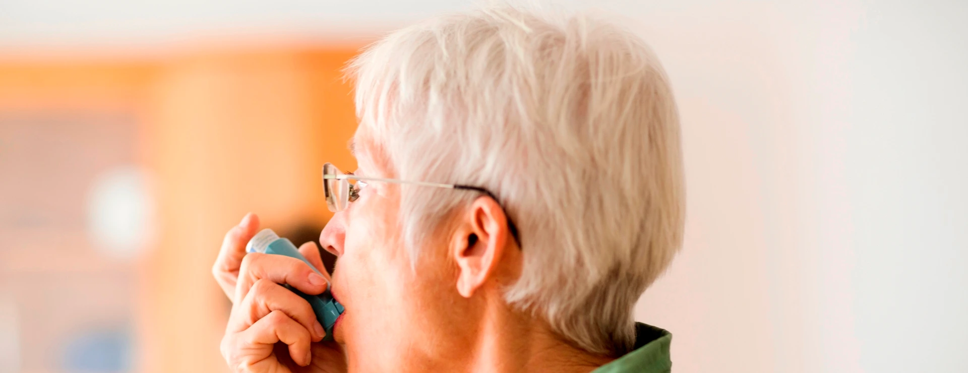 White-haired senior woman using inhaler