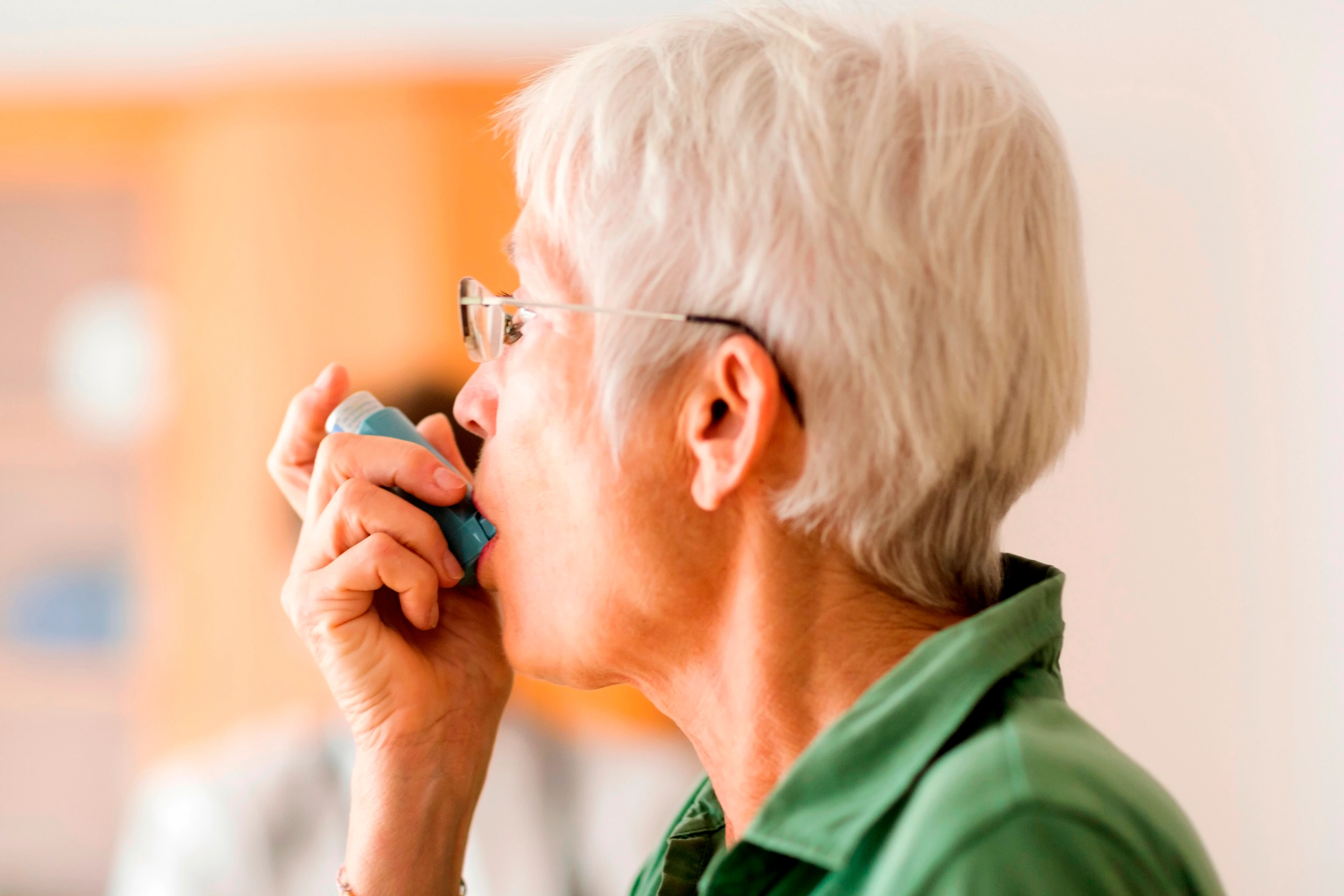 White-haired senior woman using inhaler