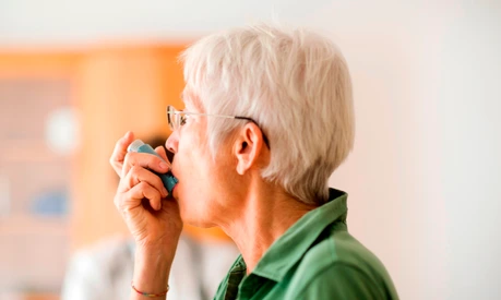 White-haired senior woman using inhaler