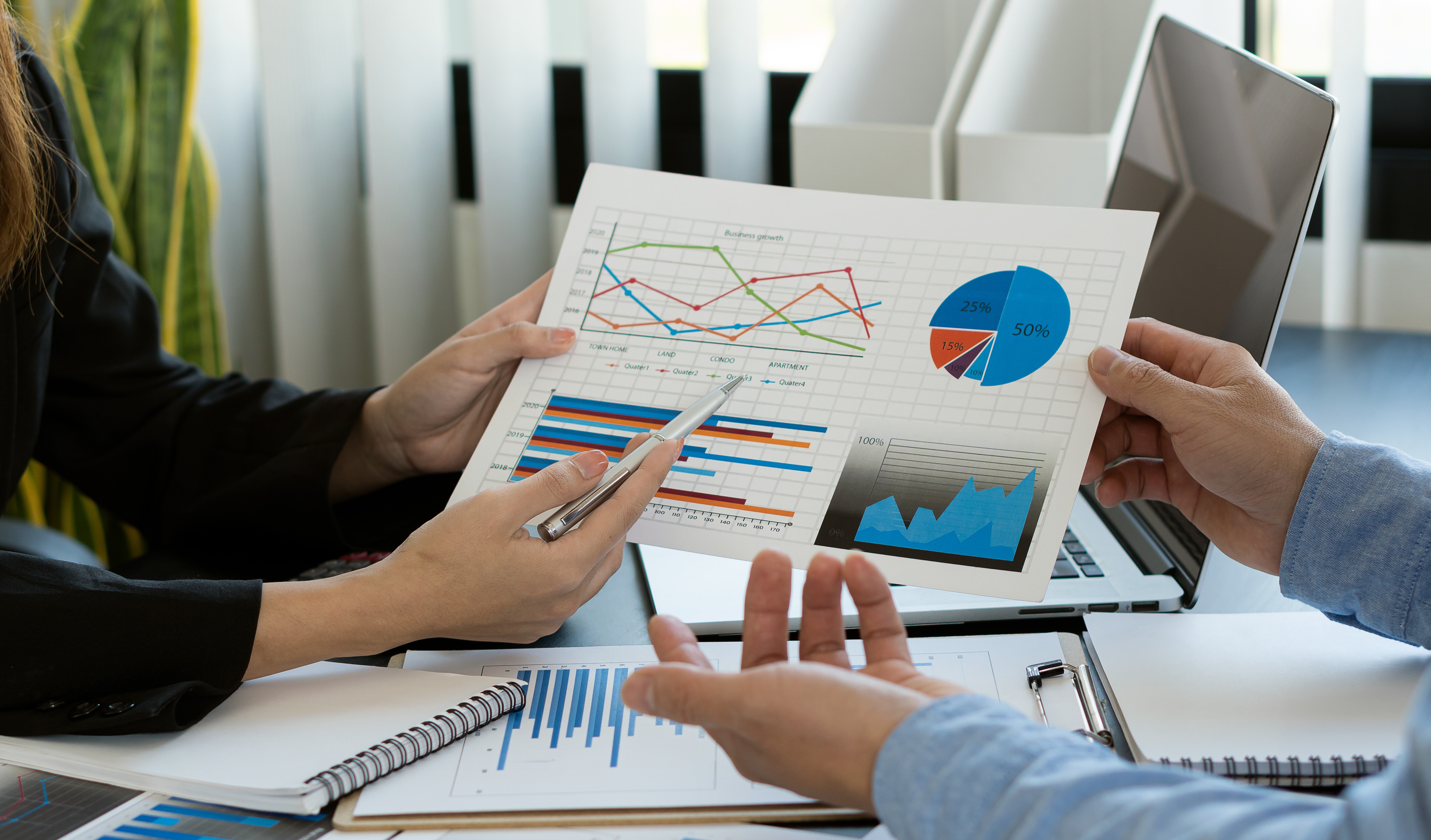 Young businessman working with laptop and graphing documents in company's multi-analysis and calculations.