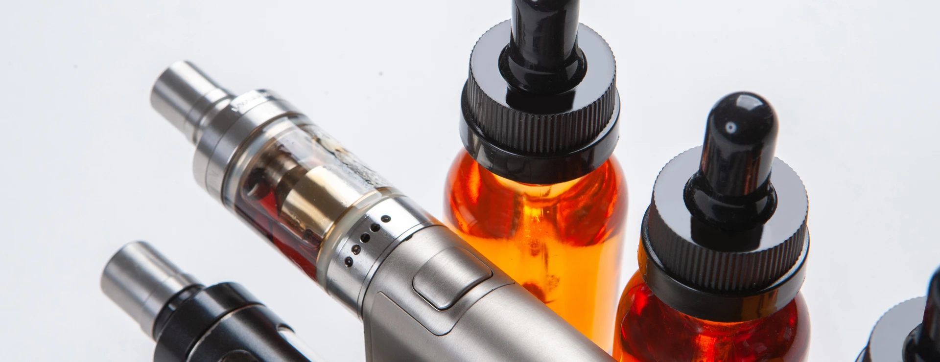Silver and black vapes next to the vials. Liquids for electronic cigarettes. Smoking e-cigarettes. Vaping accessories. Devices for Smoking electronic cigarettes.