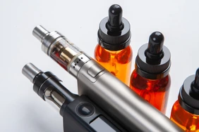 Silver and black vapes next to the vials. Liquids for electronic cigarettes. Smoking e-cigarettes. Vaping accessories. Devices for Smoking electronic cigarettes.