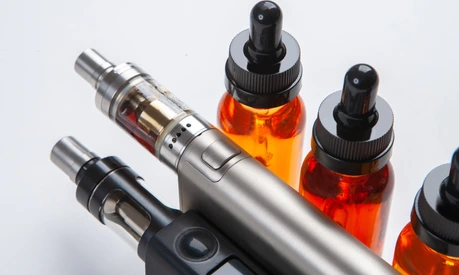 Silver and black vapes next to the vials. Liquids for electronic cigarettes. Smoking e-cigarettes. Vaping accessories. Devices for Smoking electronic cigarettes.