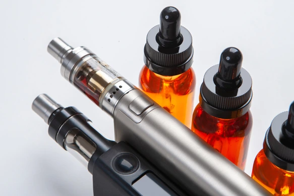 Silver and black vapes next to the vials. Liquids for electronic cigarettes. Smoking e-cigarettes. Vaping accessories. Devices for Smoking electronic cigarettes.