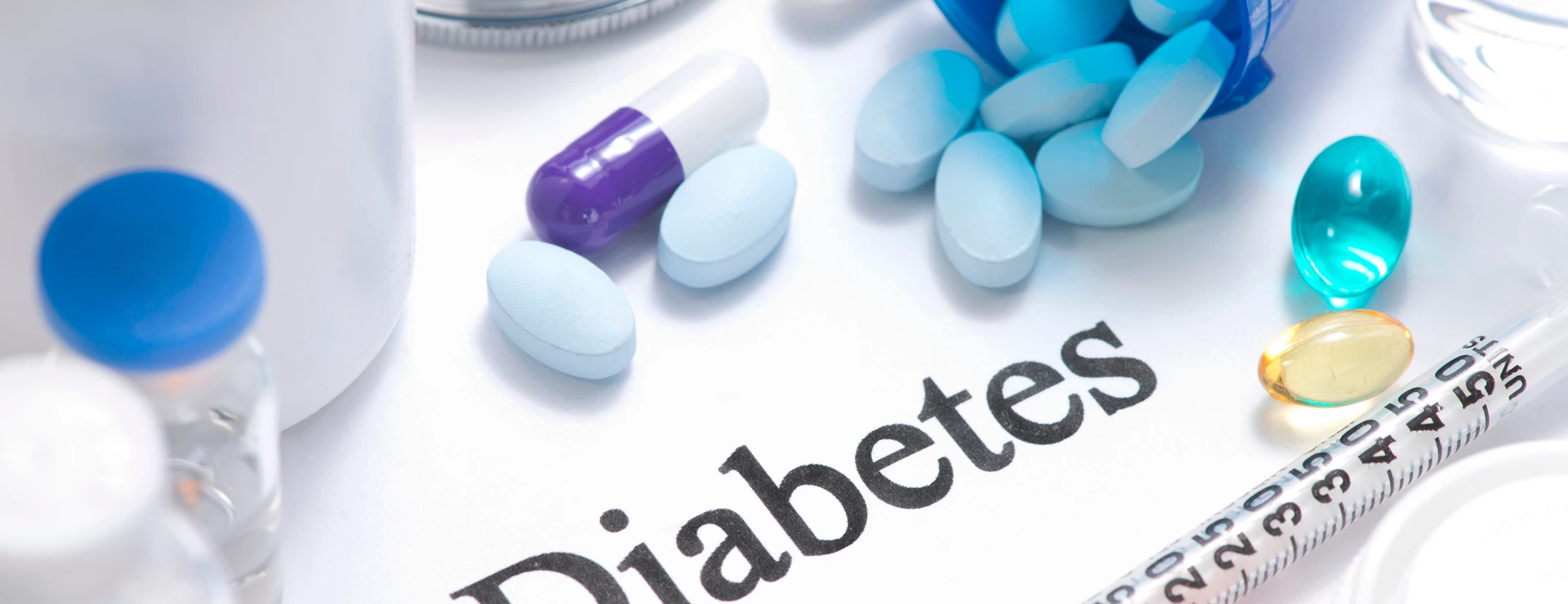 Diabetes concept with insulin, syringe, vials, pills, and stethoscope.