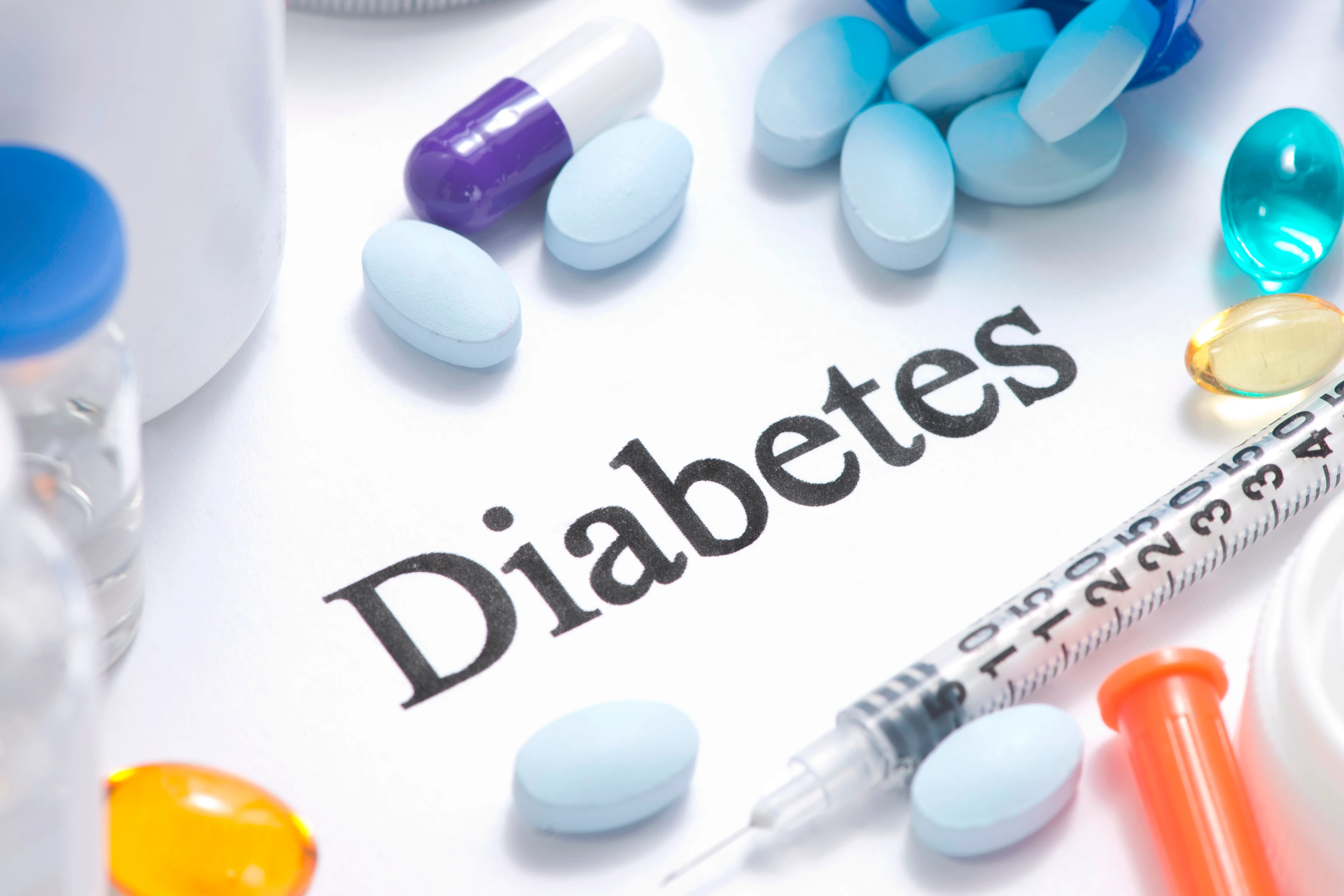 Diabetes concept with insulin, syringe, vials, pills, and stethoscope.