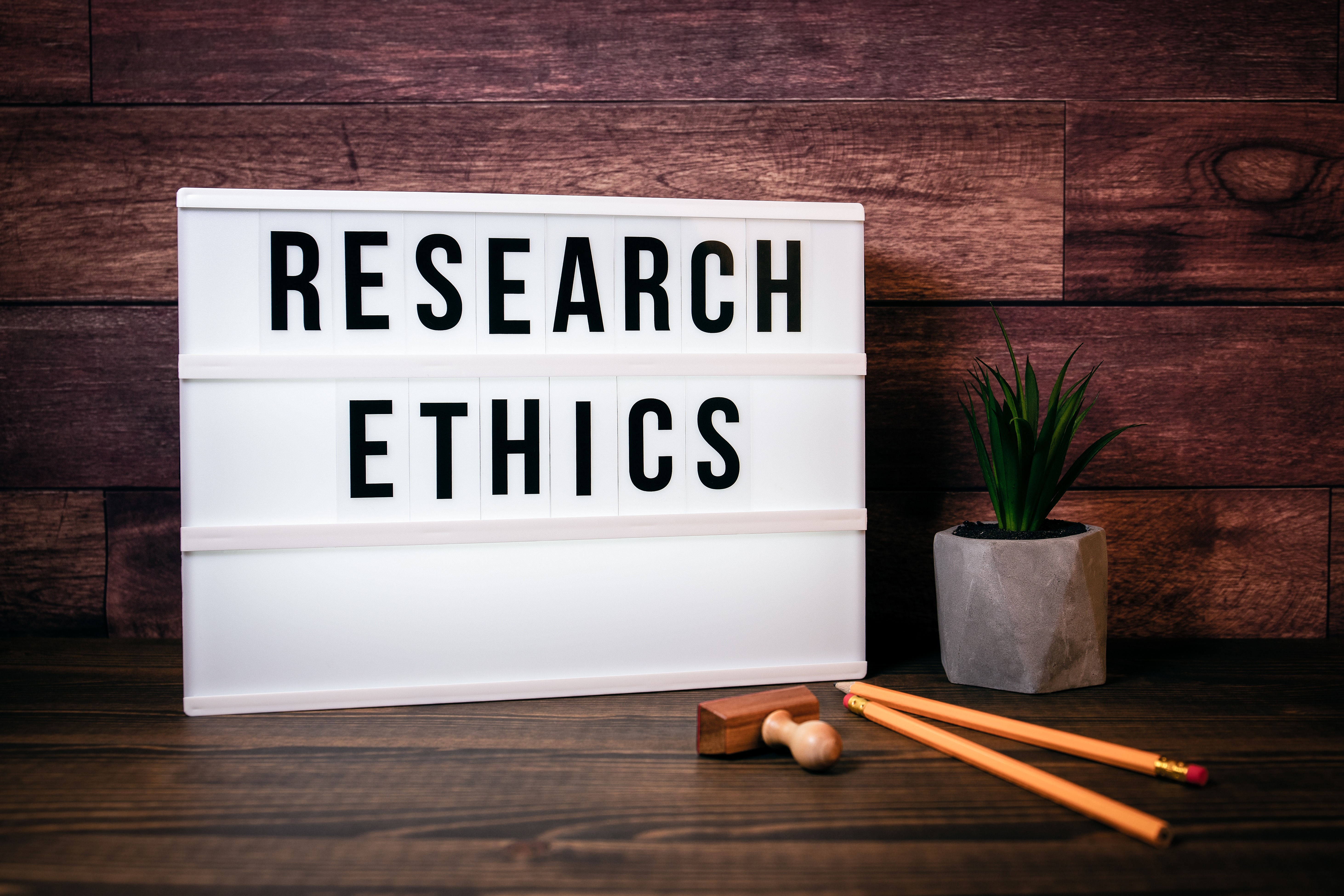 Research Ethics. Text in lightbox. Wooden office table
