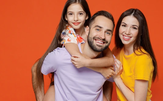 Young fun happy parents mom dad with child kid daughter teen girl in basic t-shirts giving piggyback to daughter isolated on yellow background studio portrait. Family day parenthood childhood concept