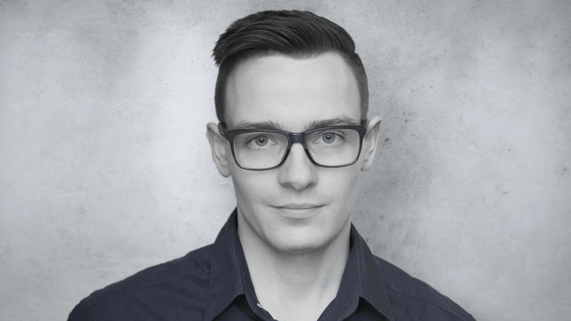 Junger Mann mit Brille und dunklem Hemd schaut ruhig in die Kamera, PALMBERG