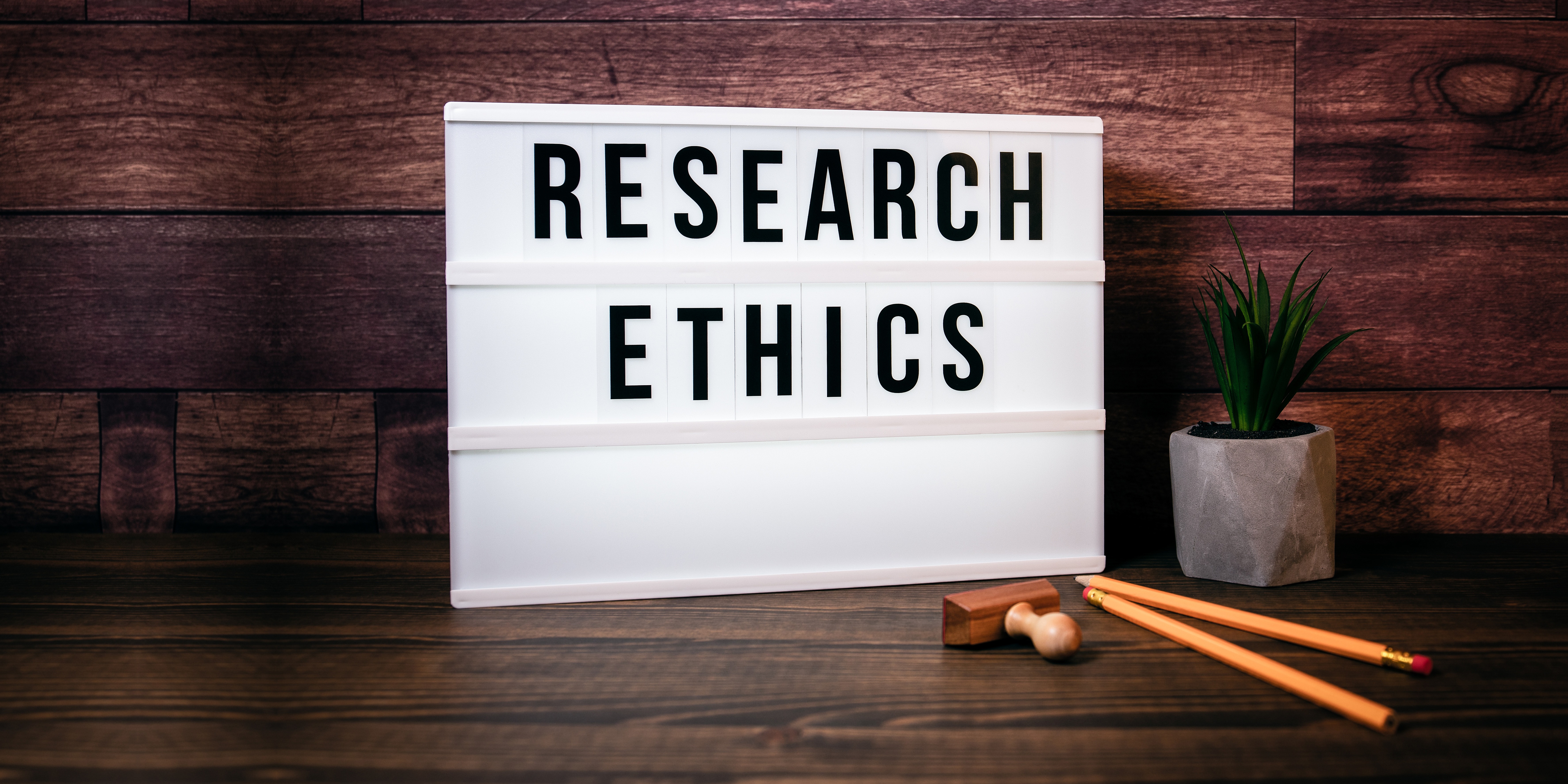 Research Ethics. Text in lightbox. Wooden office table