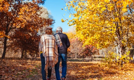 Fall activities. Senior couple walking in autumn park. Middle-aged man and woman hugging and chilling outdoors