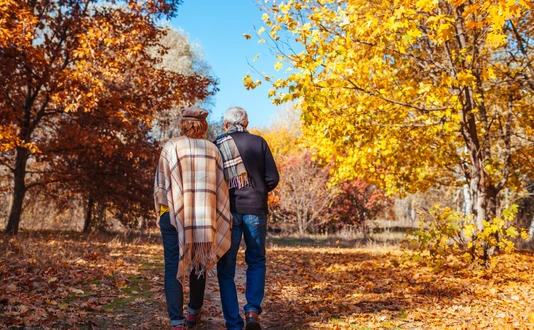 Fall activities. Senior couple walking in autumn park. Middle-aged man and woman hugging and chilling outdoors