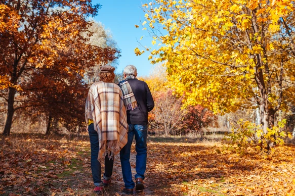 Fall activities. Senior couple walking in autumn park. Middle-aged man and woman hugging and chilling outdoors