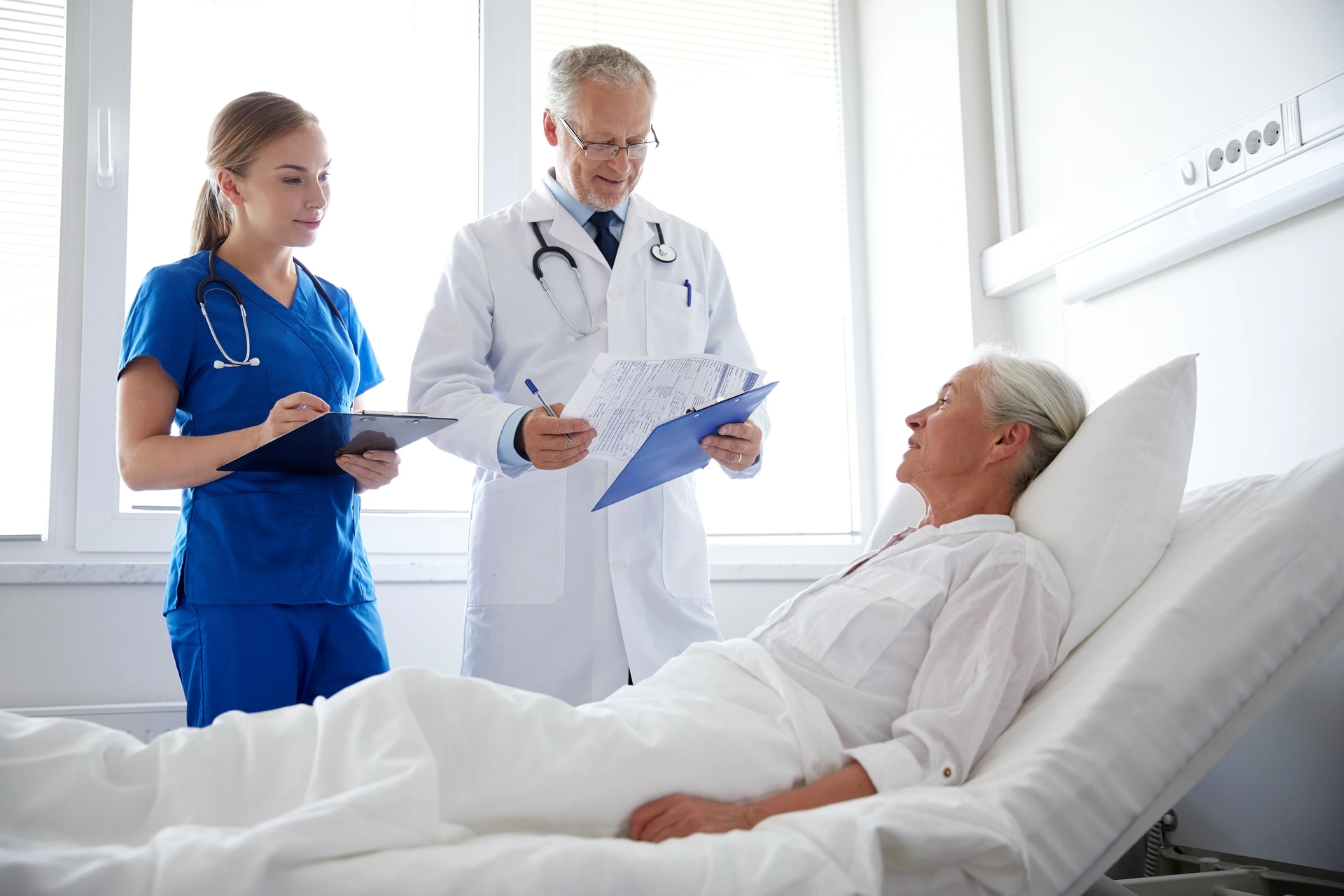 doctor and nurse visiting senior woman at hospital