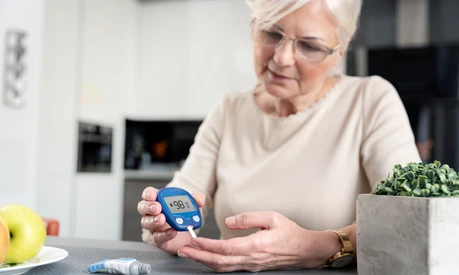 Senior woman checking blood sugar level at home