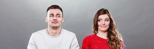 Shy woman and man sitting on sofa. First date.