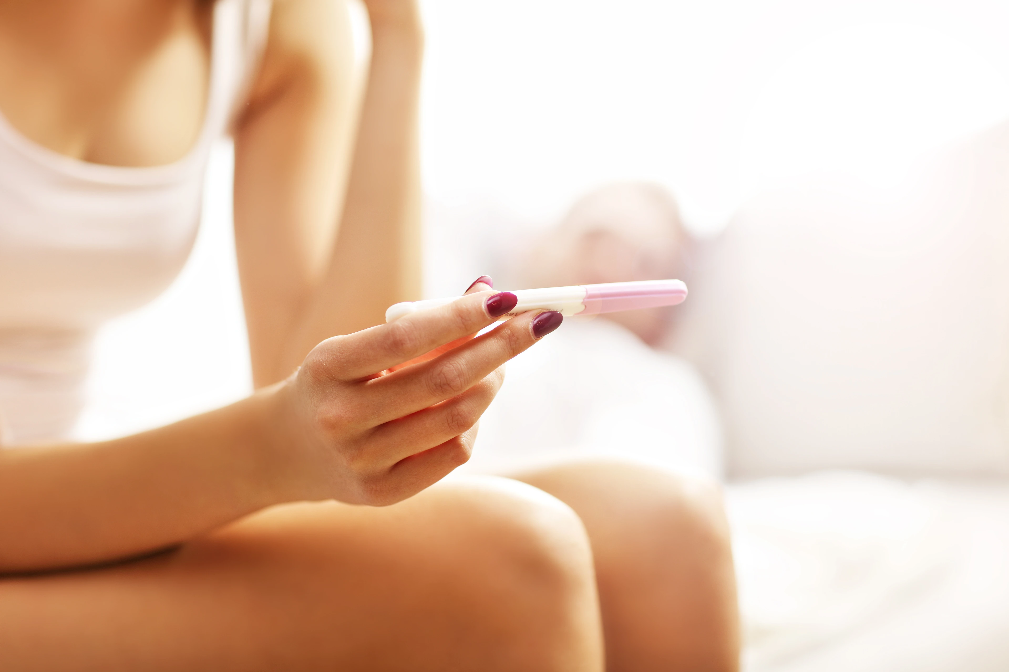 Picture showing woman with pregnancy test in bedroom