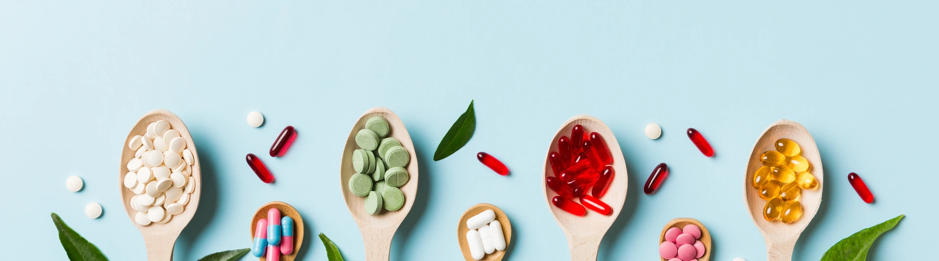 Top view Variety of vitamin and mineral pills in wooden spoon on Colored background. Top view of assorted pharmaceutical medicine pills. Dietary supplement healthcare product
