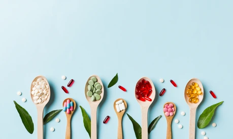 Top view Variety of vitamin and mineral pills in wooden spoon on Colored background. Top view of assorted pharmaceutical medicine pills. Dietary supplement healthcare product