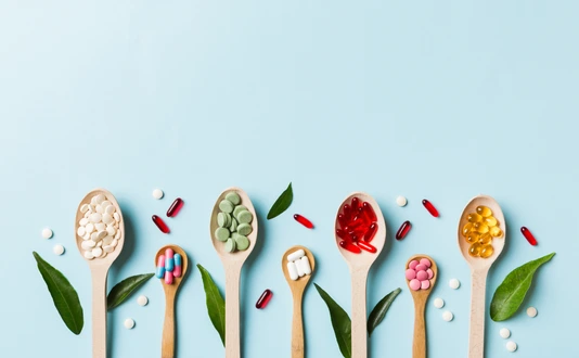 Top view Variety of vitamin and mineral pills in wooden spoon on Colored background. Top view of assorted pharmaceutical medicine pills. Dietary supplement healthcare product