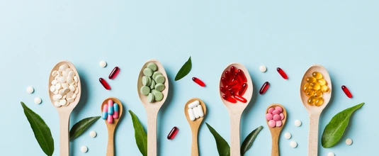 Top view Variety of vitamin and mineral pills in wooden spoon on Colored background. Top view of assorted pharmaceutical medicine pills. Dietary supplement healthcare product