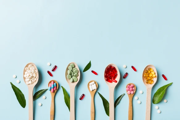 Top view Variety of vitamin and mineral pills in wooden spoon on Colored background. Top view of assorted pharmaceutical medicine pills. Dietary supplement healthcare product