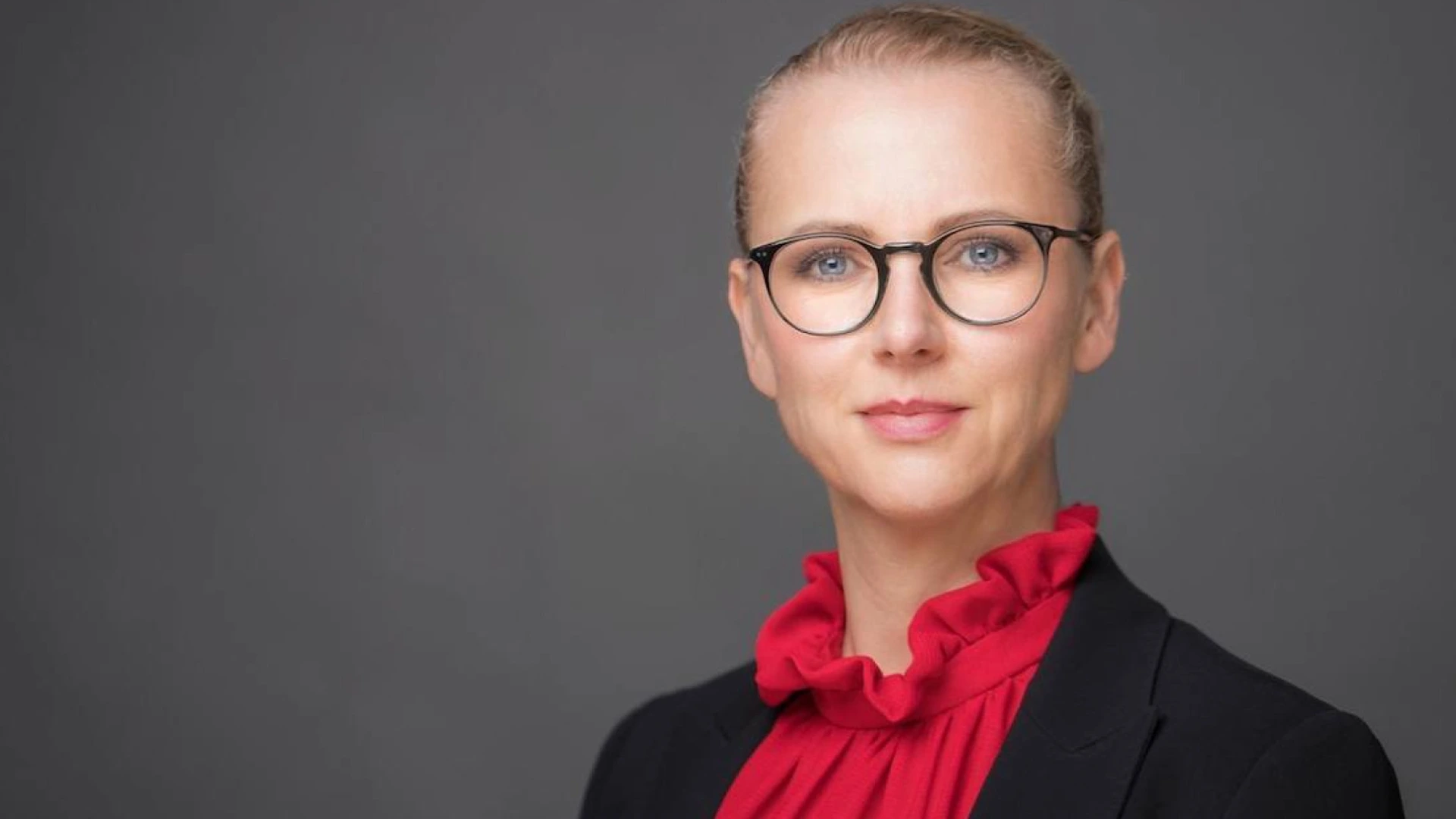 Foto einer Frau mit Brille, roter Rüschenbluse und dunklem Blazer, leichtes Lächeln PALMBERG