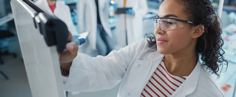 Medical Science Laboratory: Beautiful Black Female Scientist Writes Detailed Project Data Analysis on the Board, Her Diverse Team of Colleague Listens. Young Scientists Solving Problems.
