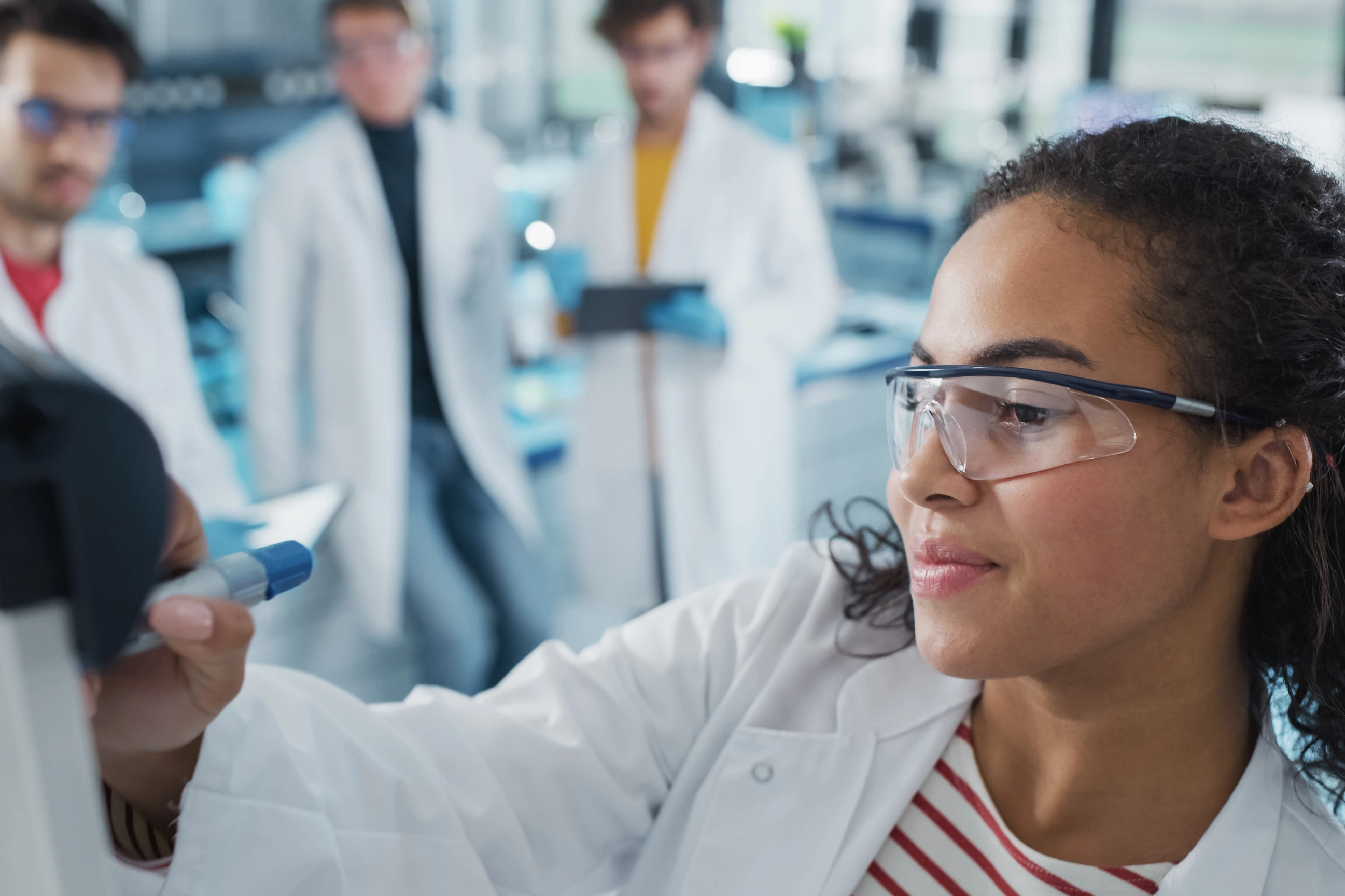 Medical Science Laboratory: Beautiful Black Female Scientist Writes Detailed Project Data Analysis on the Board, Her Diverse Team of Colleague Listens. Young Scientists Solving Problems.