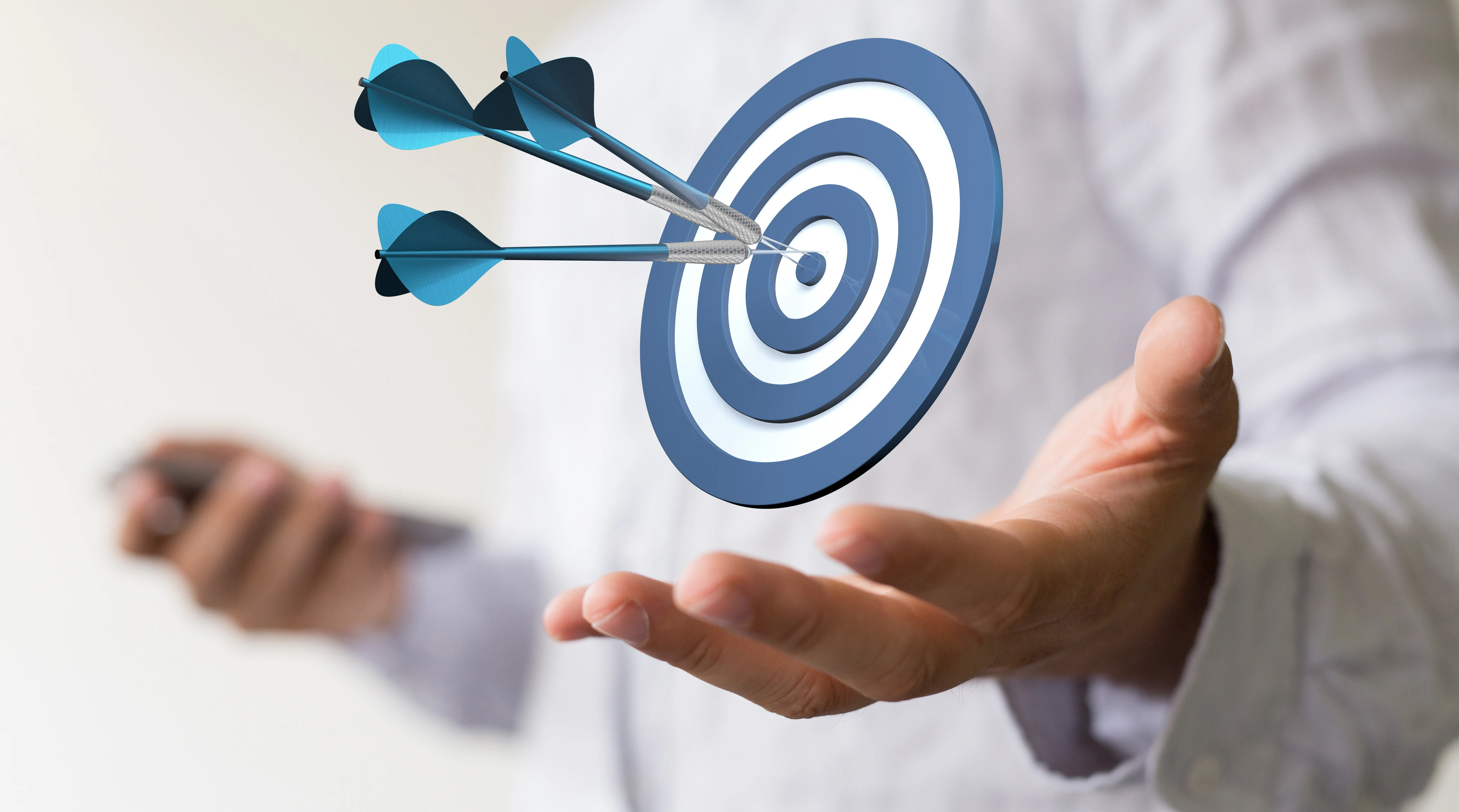 Dartscheibe mit Pfeilen über einer Hand schwebend