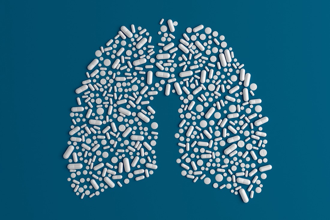 Many pills scattered on a blue uniform background in the form of a silhouette lugs man 3d illustration