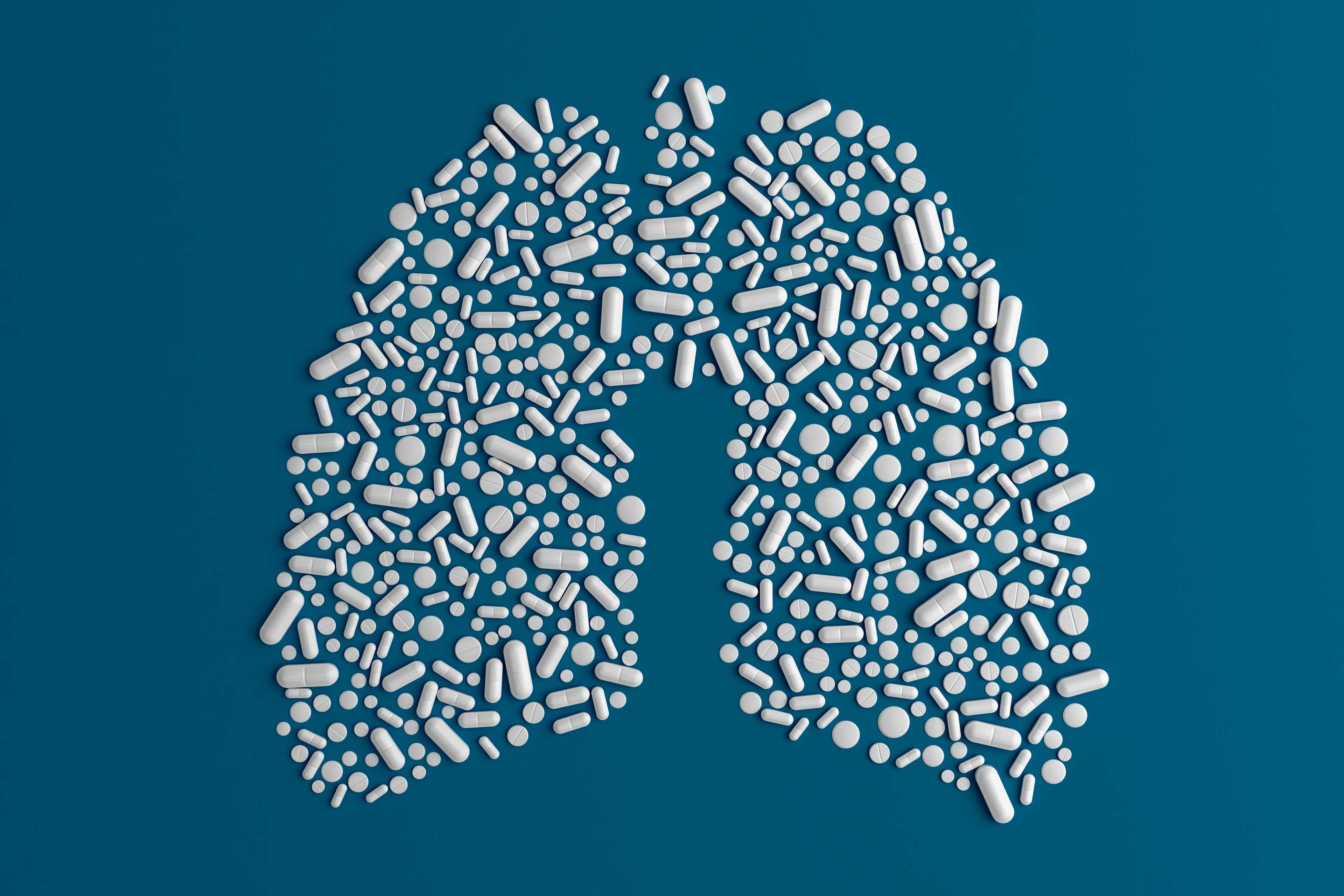 Many pills scattered on a blue uniform background in the form of a silhouette lugs man 3d illustration