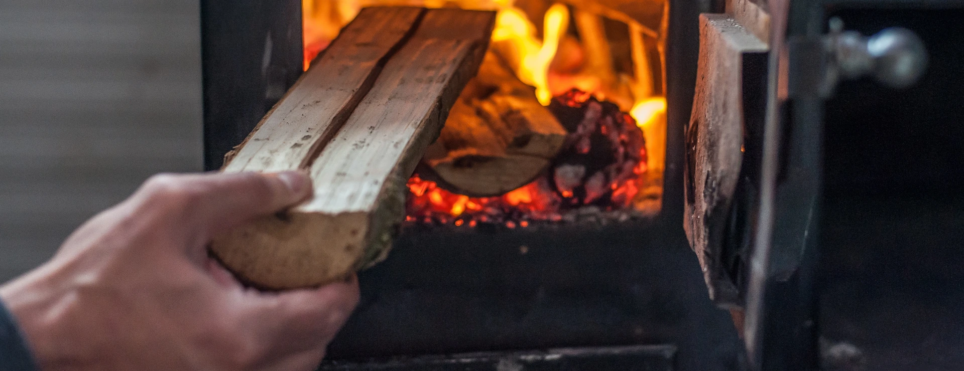 Man putting log to wood burning stove