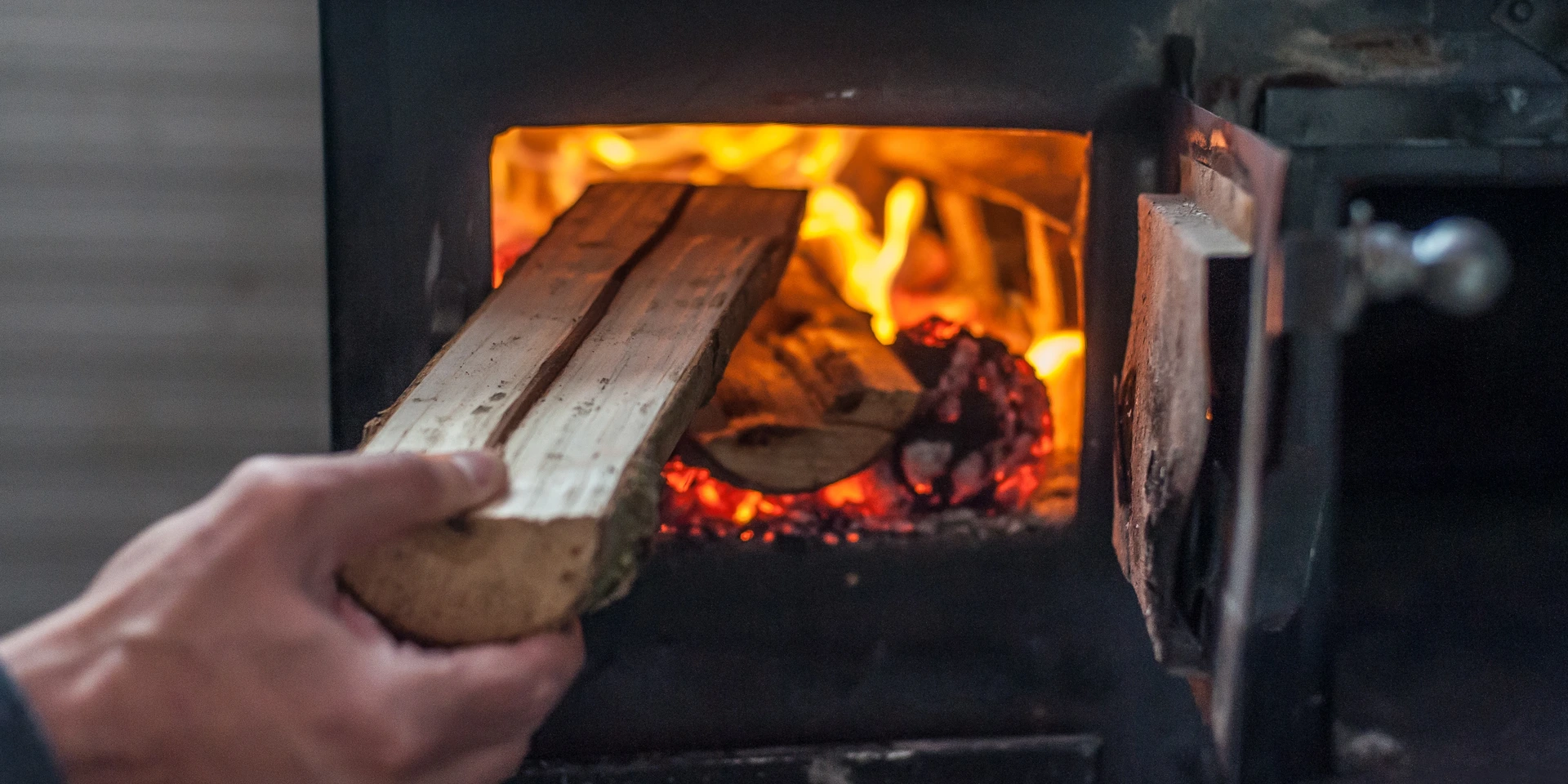 Man putting log to wood burning stove