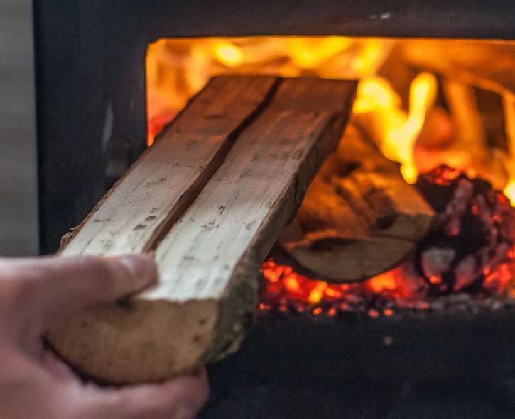 Man putting log to wood burning stove