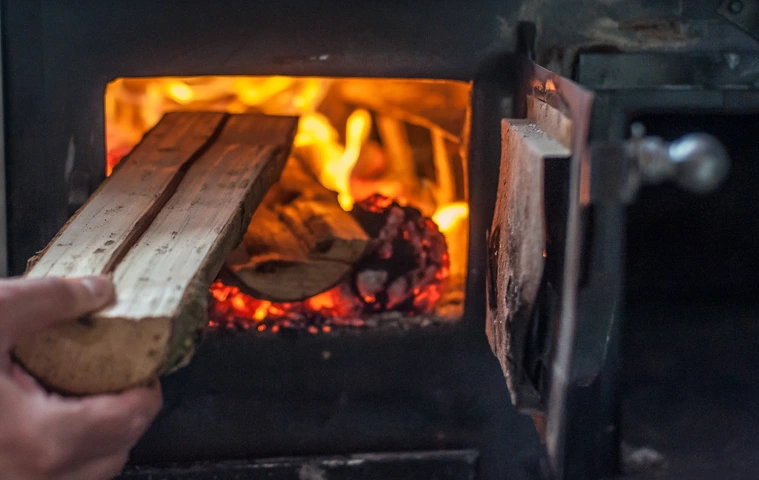 Man putting log to wood burning stove